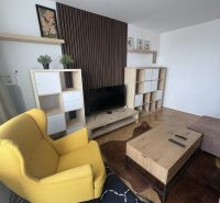 Living room with wood-patterned flooring, a yellow armchair, and a wooden coffee table.