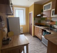 A kitchen with yellow walls, wooden furniture, and a floor with a wooden decor in a 2-room apartment.