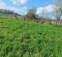 Residential plots in the village of Budiná, green pastures, and fenced areas.