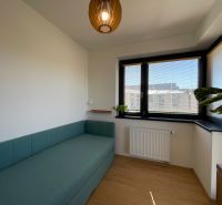A room with a sofa, windows with blinds, and a floor with a wood decor in a 2-room apartment.