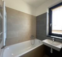 A bathroom in a 2-room apartment with a bathtub, sink, and window.