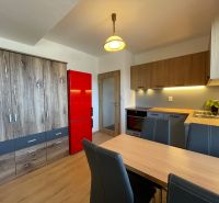 A kitchen in a 2-room apartment with cabinets featuring a wooden decor and a red refrigerator.