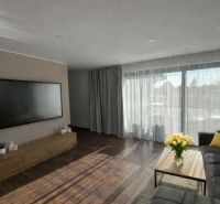 Living room in a family house with a large television, sofa, and wooden decor flooring.