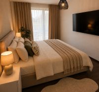 Bedroom in a family house with a bed, large TV, and floor with wooden decor.
