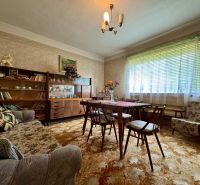 Living room in a family house with antique furniture, floral decor, and a carpet.
