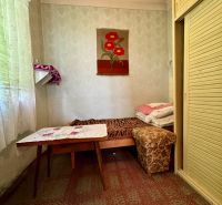 A room in a family house with a bed, a table, and a built-in wardrobe, a decorative carpet on the wall.