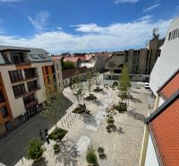 View of the Trinity Square in Trnava, with dining spaces and greenery.