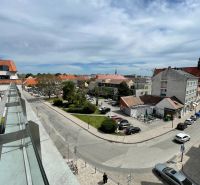 View from the Trinity Square in Trnava towards the parking lot and surrounding buildings.