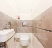 Bathroom in a family house with ceramic tiles and a toilet.