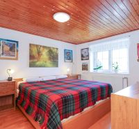 A bedroom in a family house with a wooden ceiling and a floor with a wood decor.