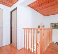 A staircase with a wooden railing and a floor with a wooden decor in a family house.