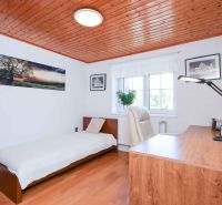 A room in a family house with a table, a chair, and a bunk bed. The floor has a wood decor.