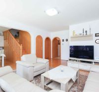 Living room in a family house with cream furniture and a wooden decor floor.