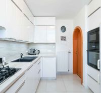 A kitchen in a family house with white cabinets and appliances, and a floor with a wooden decor.