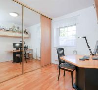 A study in a family house with a wooden decor floor and a large mirrored wardrobe.