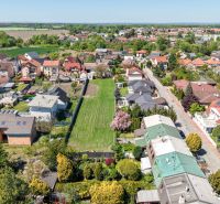 An aerial photograph shows family houses on Hollého Street in Stupava surrounded by greenery.