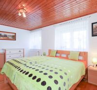 A bedroom in a family house with a wooden ceiling, decorative paintings, and a floor with a wooden decor.