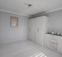 A bright room in a one-bedroom apartment with a wardrobe and decorations on the dresser.