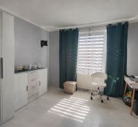 A room in a one-room apartment, light floor with wood decor, chair and table.