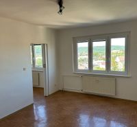 A bright room with three windows and a wooden decor floor in a two-room apartment.