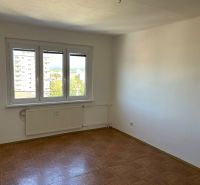 A room in a 2-room apartment with a wooden decor floor and a large window.