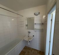 A bathroom with a bathtub in a 2-room apartment with tiled walls.