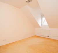 An empty room with a colorful carpet, a radiator, and a bright window in a 3-room apartment.