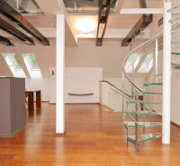 A spacious attic with a spiral staircase and a wooden decor floor in a 3-room apartment.