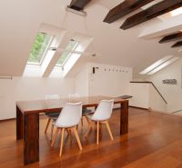 A bright dining room in a three-room apartment with wood-patterned flooring and skylights.