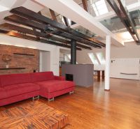 Attic living space with a large red sofa and wood-patterned flooring in a 3-room apartment.