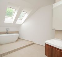 A bathroom with skylights, a freestanding bathtub, and a sink in a three-room apartment.