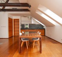 Dining area in a 3-room apartment with a wood-patterned floor and wooden beams.