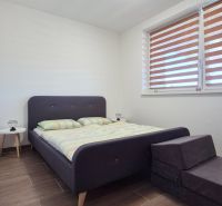 Bedroom with a bed, nightstand, and wooden decor flooring in a family house.