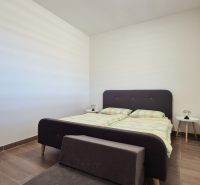 A bedroom in a family house with a bed and nightstands, flooring with a wooden decor.