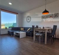 Living room in a family house with wood-patterned flooring, a sofa set, and a dining table.