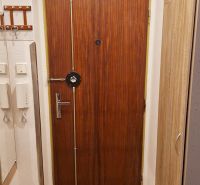 Entrance door with wood decor in a 3-room apartment, secured with a steel bar.