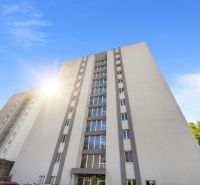A high-rise apartment building in Bratislava - Old Town with a blue sky and a parking lot.