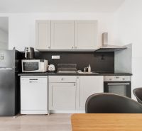 A kitchen in a 2-room apartment with equipment on a floor with a wooden decor.