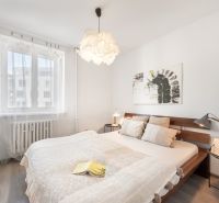 A bright bedroom with a wooden bed, a painting on the wall, and a floor with a wooden decor.