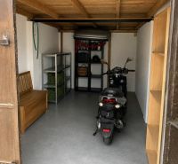Garage with a motorcycle, wooden ceiling, and storage shelves.