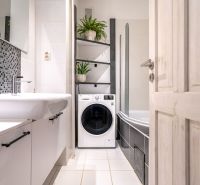 A bathroom in a 3-room apartment with a washing machine, bathtub, and mosaic tiles.