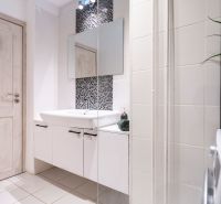 Bathroom in a 3-room apartment with white tiles, a sink, and a washing machine.