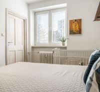 Bedroom in a 3-room apartment with a bed, a plant, and a decorative painting on the wall.