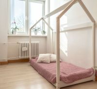 A children's room with a mattress on the floor with wooden decor in a 3-room apartment.