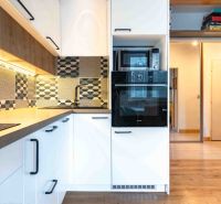 A kitchen in a 3-room apartment with patterned tiles and a floor with a wooden decor.