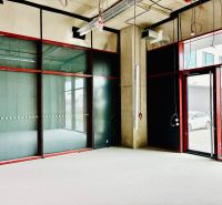 Interior of commercial spaces with glass window walls and raw floor surface.