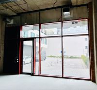 Commercial spaces with large glass doors and raw concrete walls.