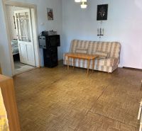 A living room in a family house with a sofa and a wood-patterned floor.