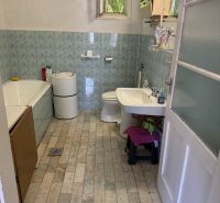 The bathroom in the family house has tiled walls and flooring.