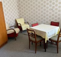A room in a family house with retro furniture, wallpaper, and carpeted floor.